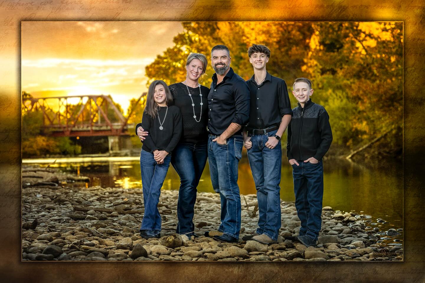Family portrait at sunset beside a river bridge