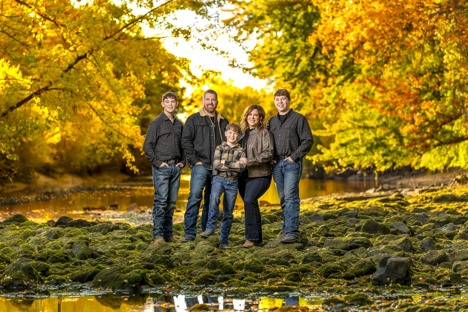 Family portrait among golden autumn trees by a river